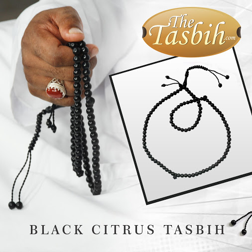 Hand holding a jet black dyed citrus wood tasbih with extra counters.